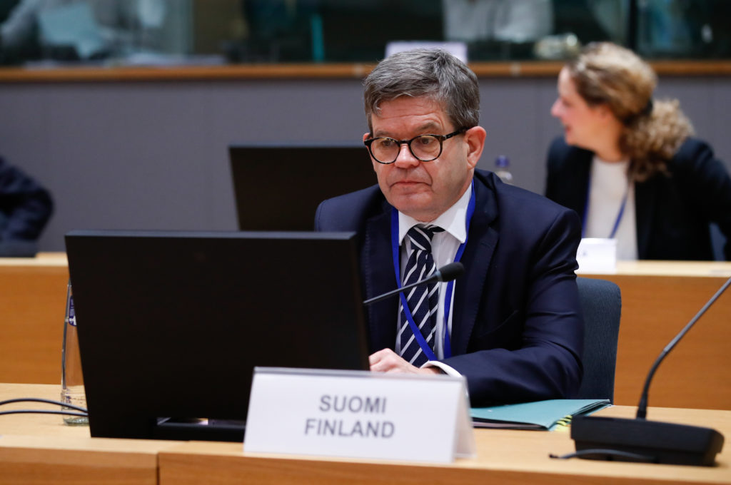 Chefen för Finlands ständiga representation vid EU Markku Keinänen sitter vid mötesbordet, framför sig är skylten Suomi Finland.