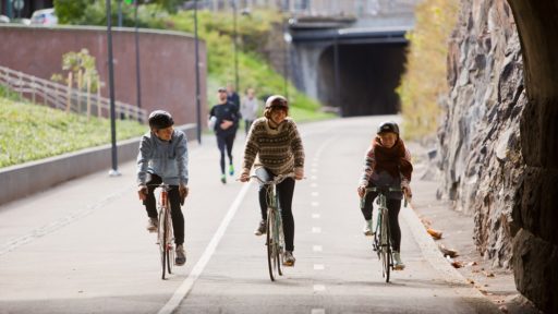 Kolme pyöräilijää Baana-väylällä Helsingissä.