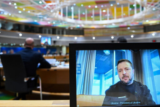 Kuvassa Ukrainan presidentti Zlenskyi näkyy näyttöruudulla, taustallaan Eurooppa-neuvoston kokoussali.